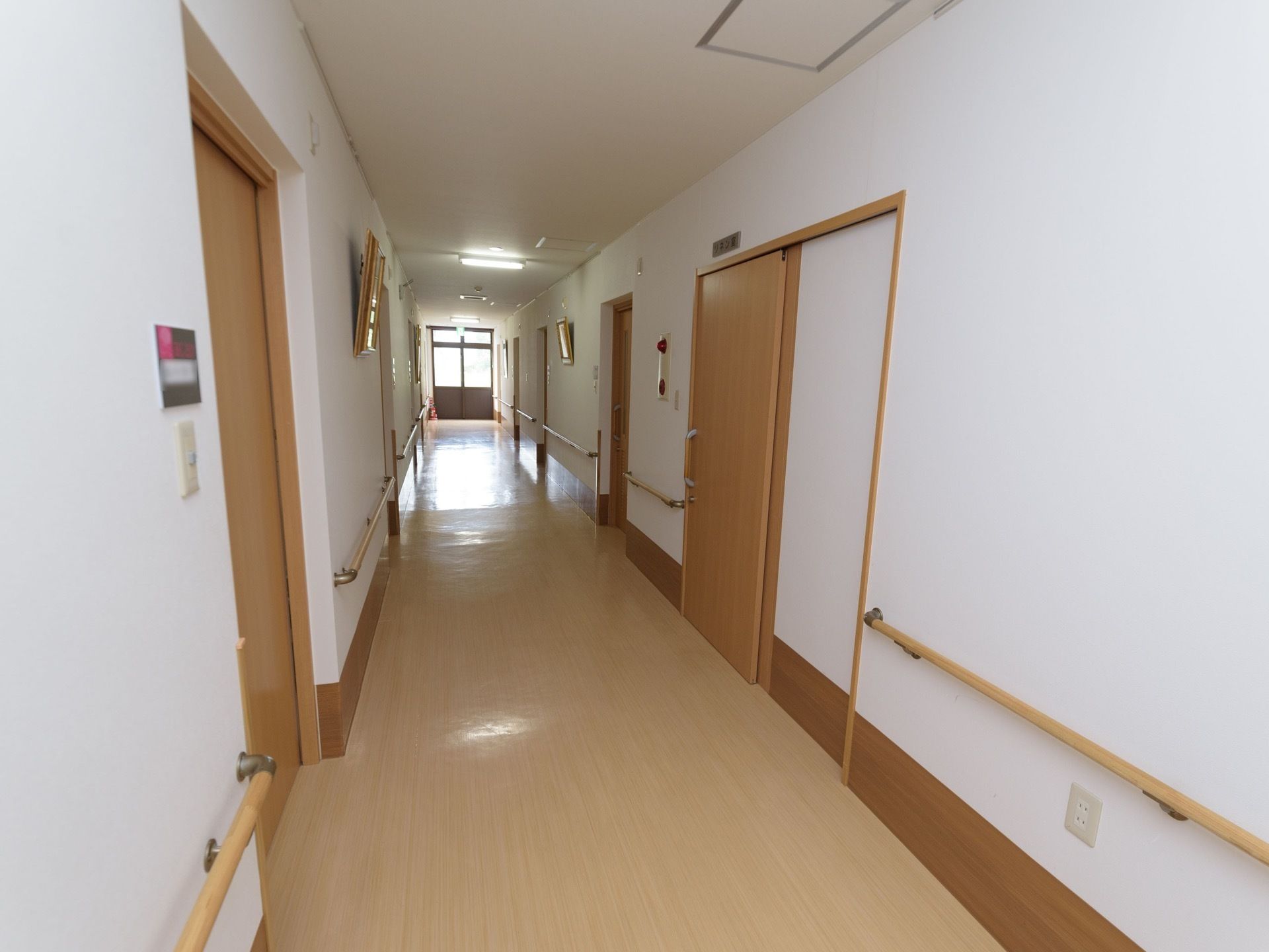 見通しが良く明るい廊下である。両サイドに居室が設けられており、手すりが壁に沿って取り付けられている。