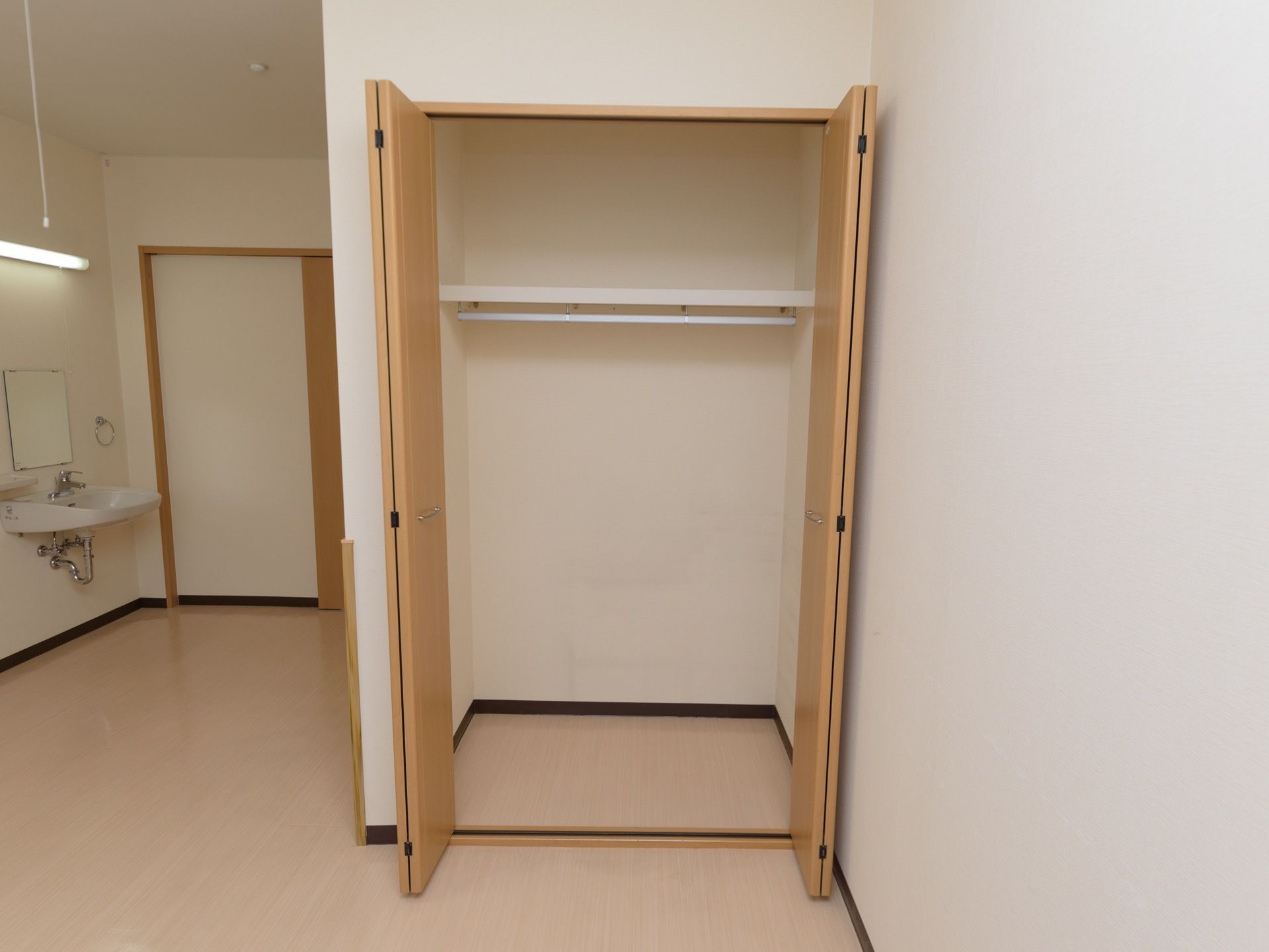 居室には、内部が２段に分かれた折れ戸付きクローゼットが完備されている。出入り口付近の壁には、洗面台が設置されている。