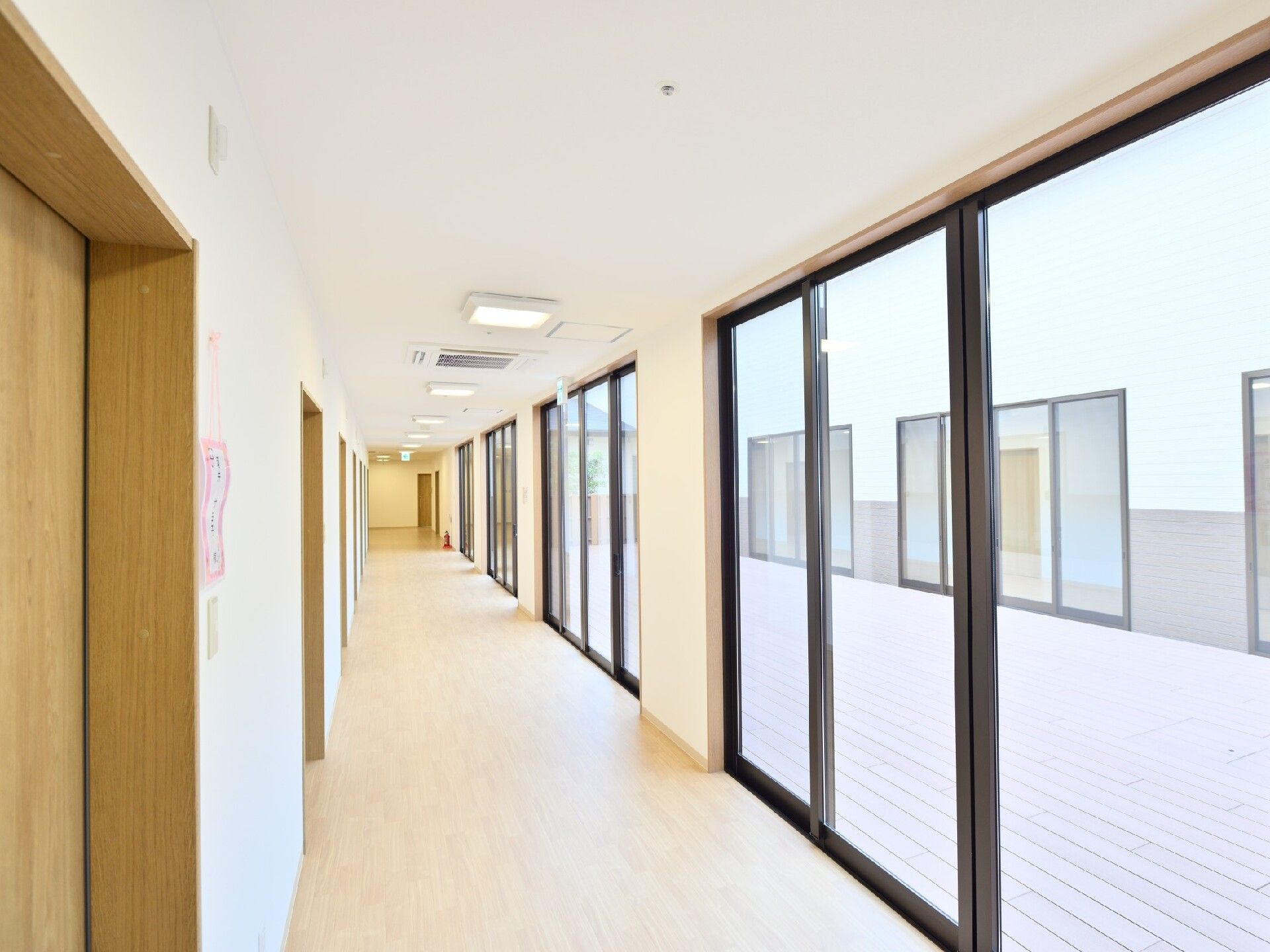 まっすぐな廊下は右側に大きな窓が、左側には居室のドアが並び、明るい雰囲気。居室のドアは木製でスライド式。