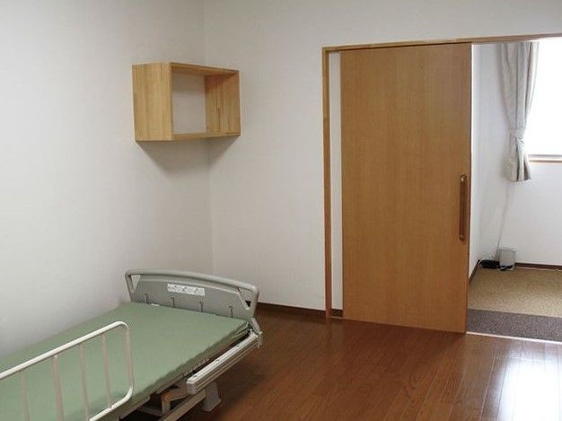 引き戸と介護用のリクライニングベッドが設置されている個室