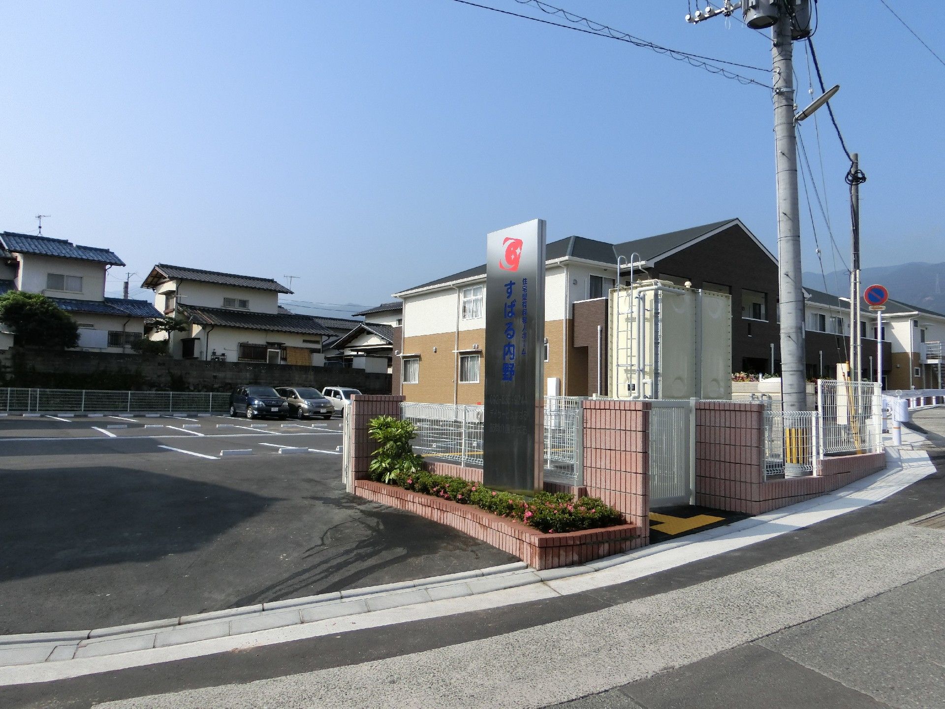 ２階建ての施設の建物外観と、隣接する広々とした専用の駐車場