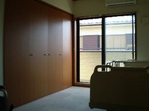 木材の扉の広いクローゼットと、介護用ベッドが設置されている部屋