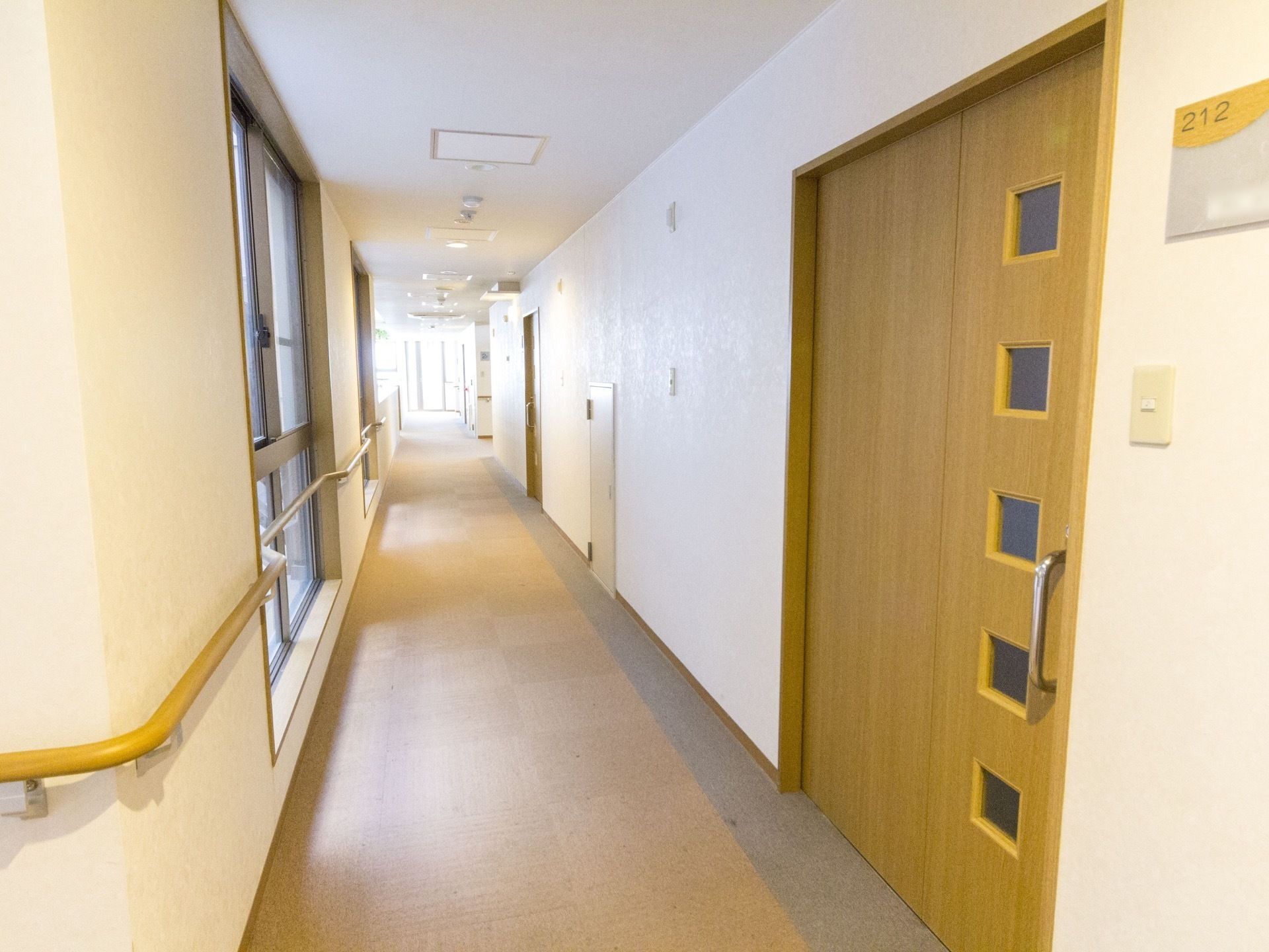 木目調の大きめのスライドドアが設置されていて、すりガラスの小窓がいくつかある。壁にはベルが設置されている。