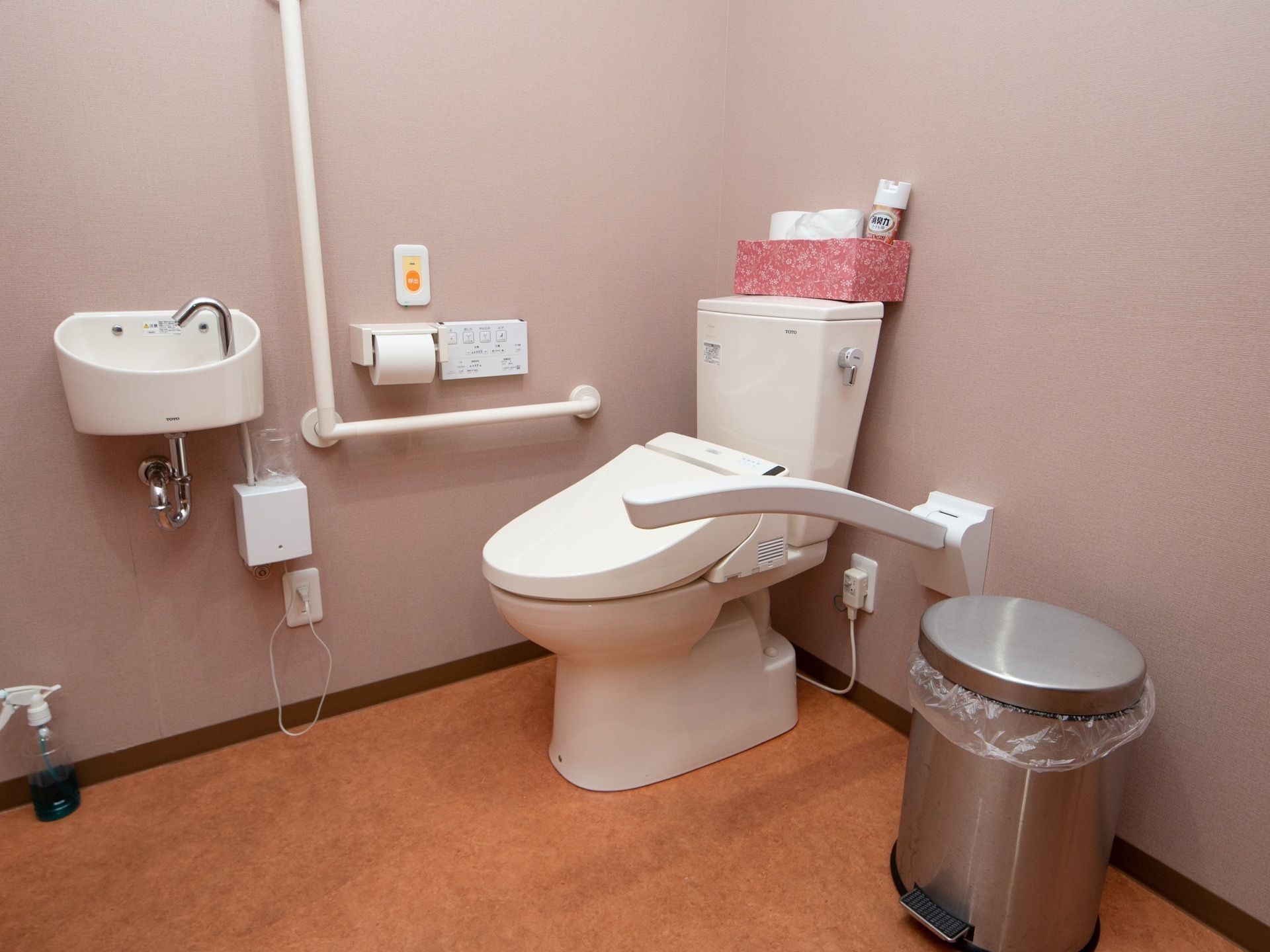 広いスペースのある洋式トイレで、便器の脇に可動式の手すりが備わっている。手洗い場やナースコールも設置されている。