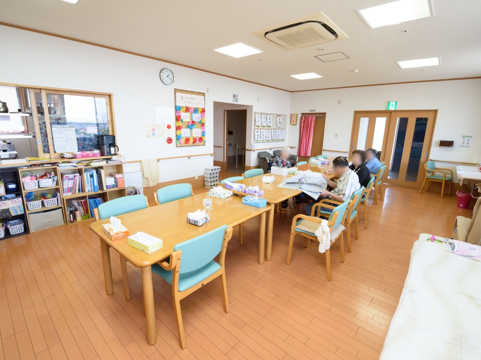 厨房が併設されている食堂で、ガラス窓から中が見える。角には洗面台が設置されており、椅子が置かれている。