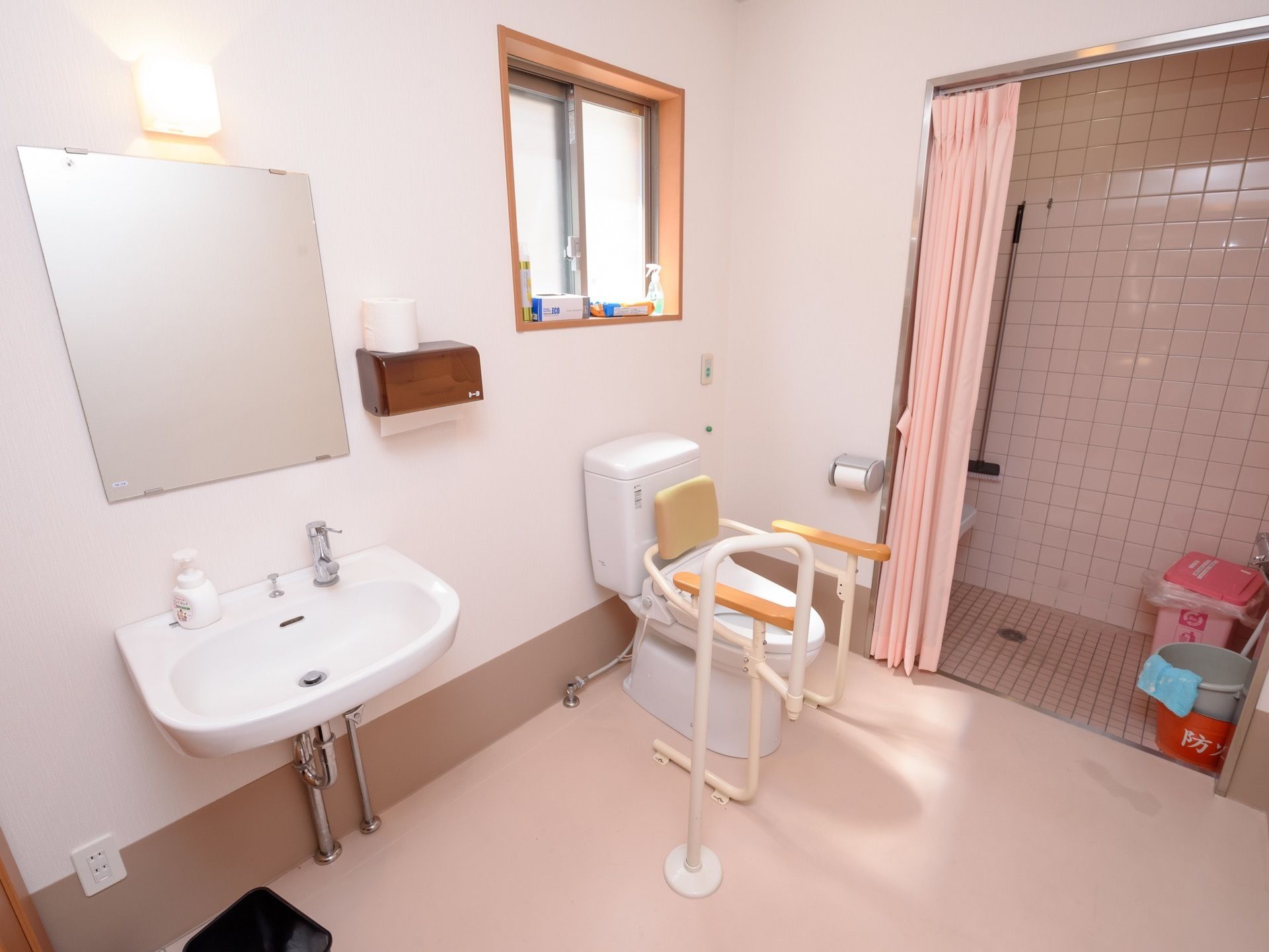 洗面台が備えつけてある個室トイレで、ハンドソープやペーパータオルが用意されている。床にごみ箱が置かれている。