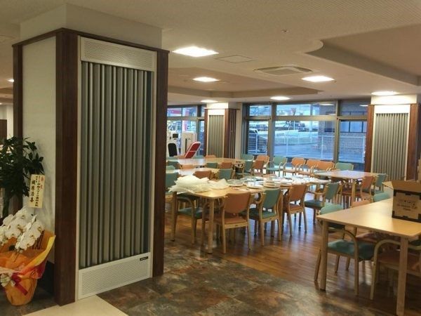 空調システム付きの柱が複数設置されている。フローリングの床となっており、手前に大きな花が飾られている。