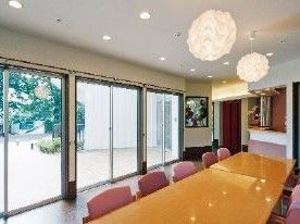 開放的なリビング中央に、ダイニングテーブルと椅子が複数置かれている。天井にはデザイン性のある球体の照明が複数設置されている。