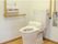 きれいに磨かれた洋式のトイレがあり、壁に取り付けられたボタンにより洗浄等の動作を行うことができる。床は、フローリングになっている。