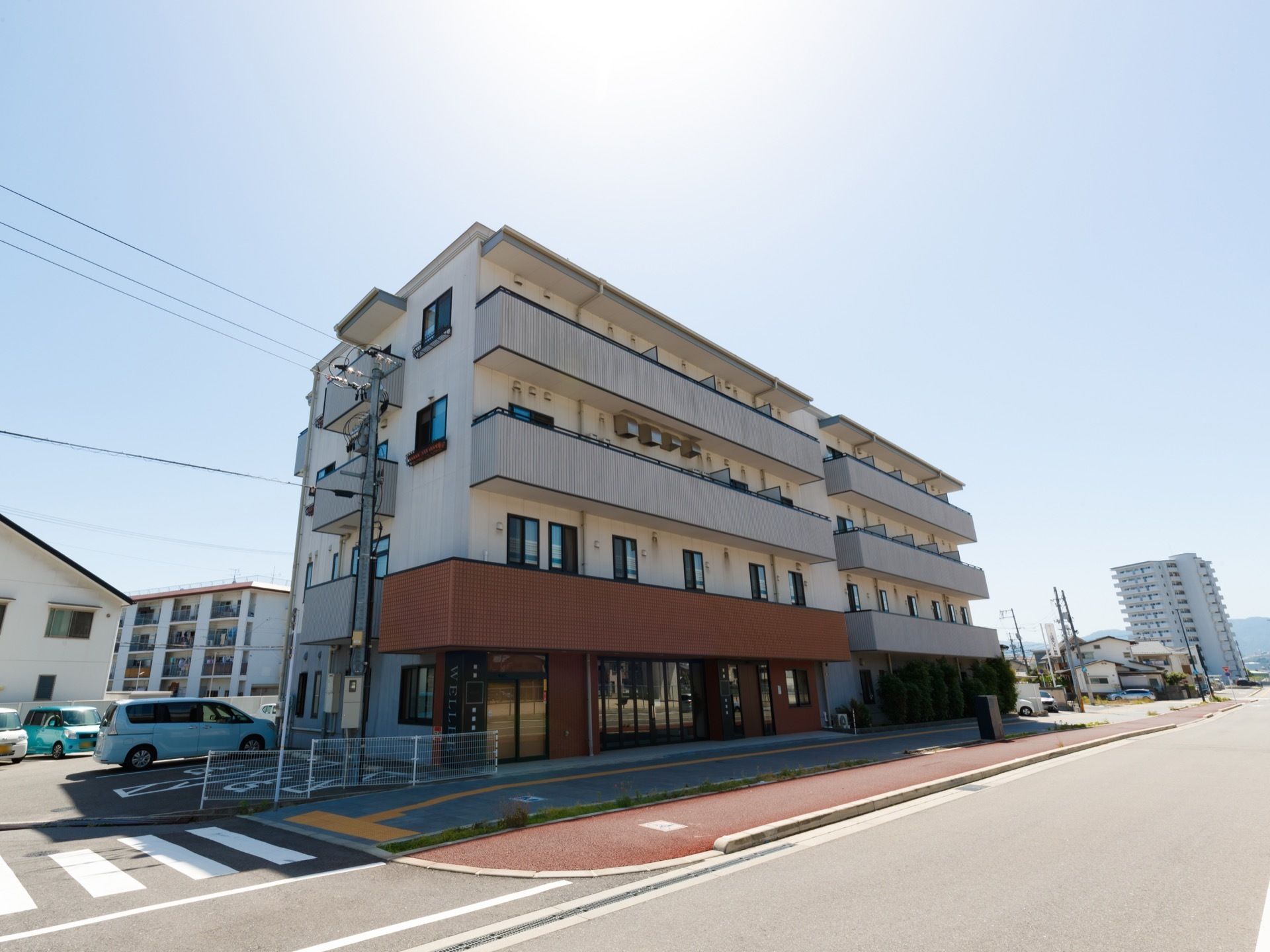 パールホワイトの外壁がさわやかな、清潔感のある外観である。一階部分の、出入り口周辺の外壁は赤褐色になっている。