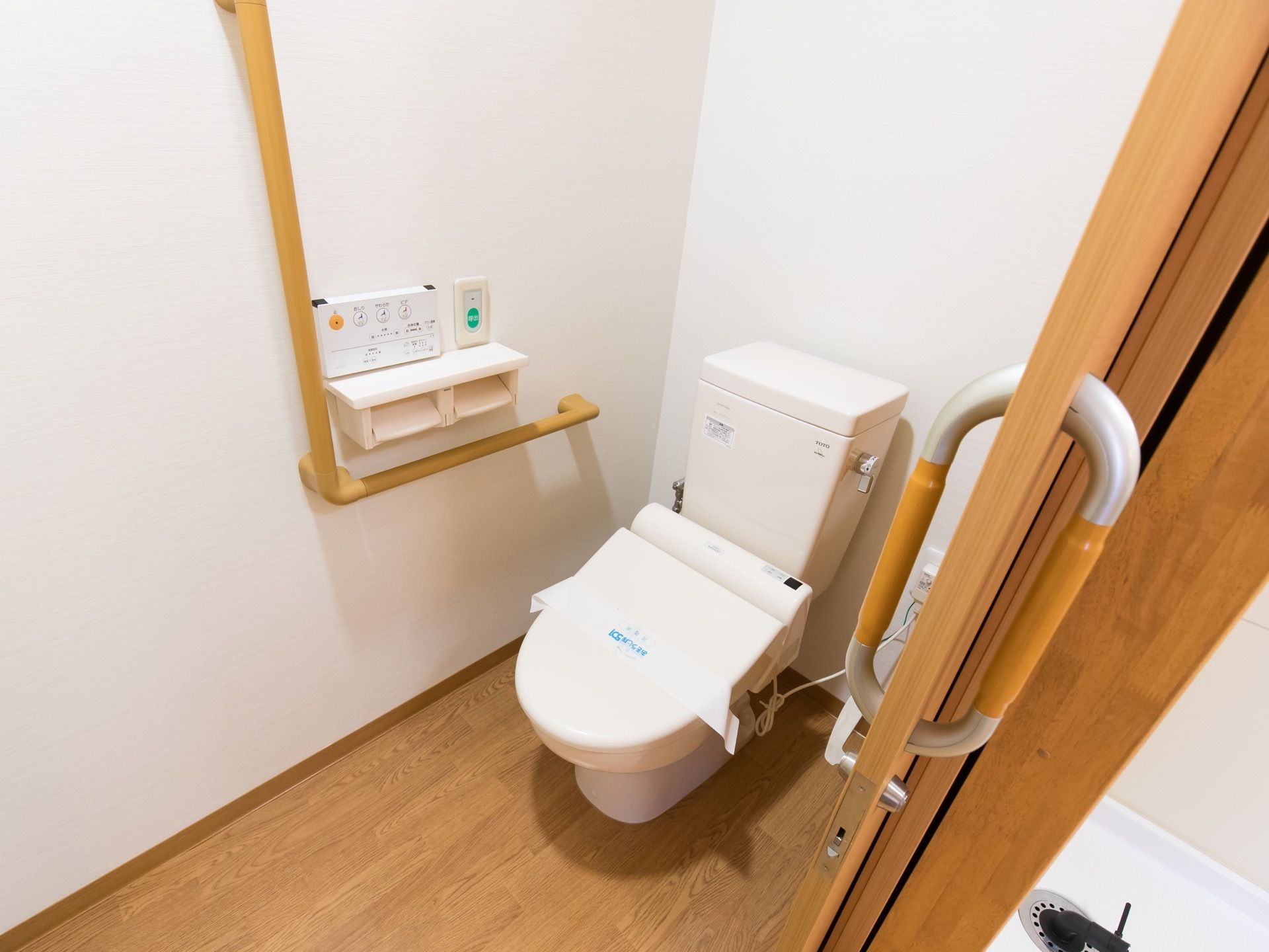 フローリングの床がオシャレなトイレだ。ドアは引き戸で出入りしやすく、便座の横の壁には手すりが設置されている。
