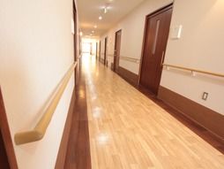 廊下の幅は十分に広く、両側の壁には手すりが設置され安全性が確保されている。各居室へ通じる引き戸が並んでいる。