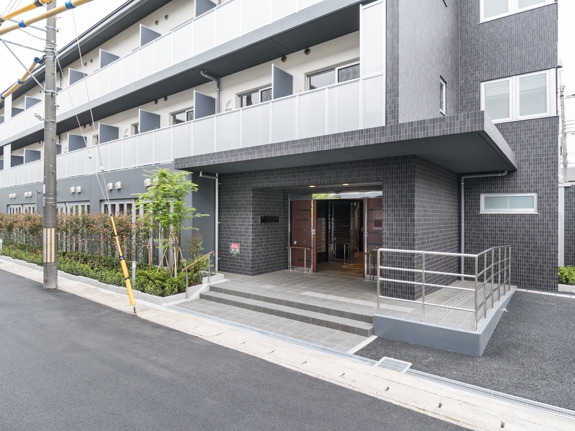 ３階建てのブラックの外壁がお洒落なグループホームである。２階以上には転落防止の柵が付いたベランダが設置されている。