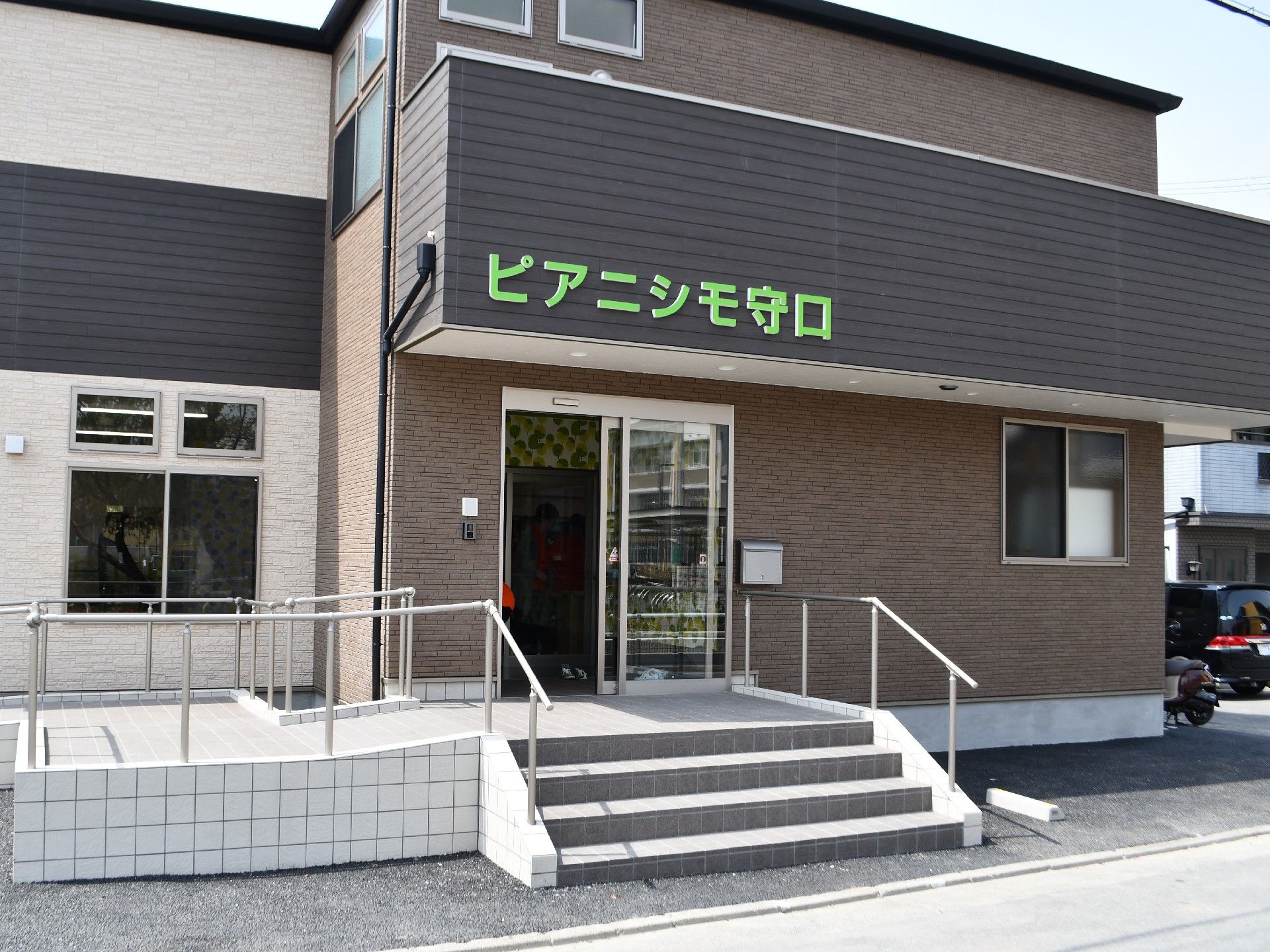 玄関前に手すり付きの階段とスロープが設置された建物