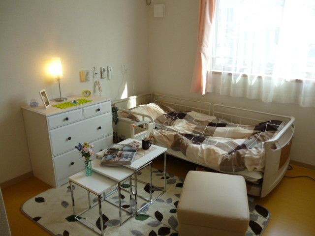 ベッドやタンス、テーブルが置かれている白い壁の可愛らしい部屋