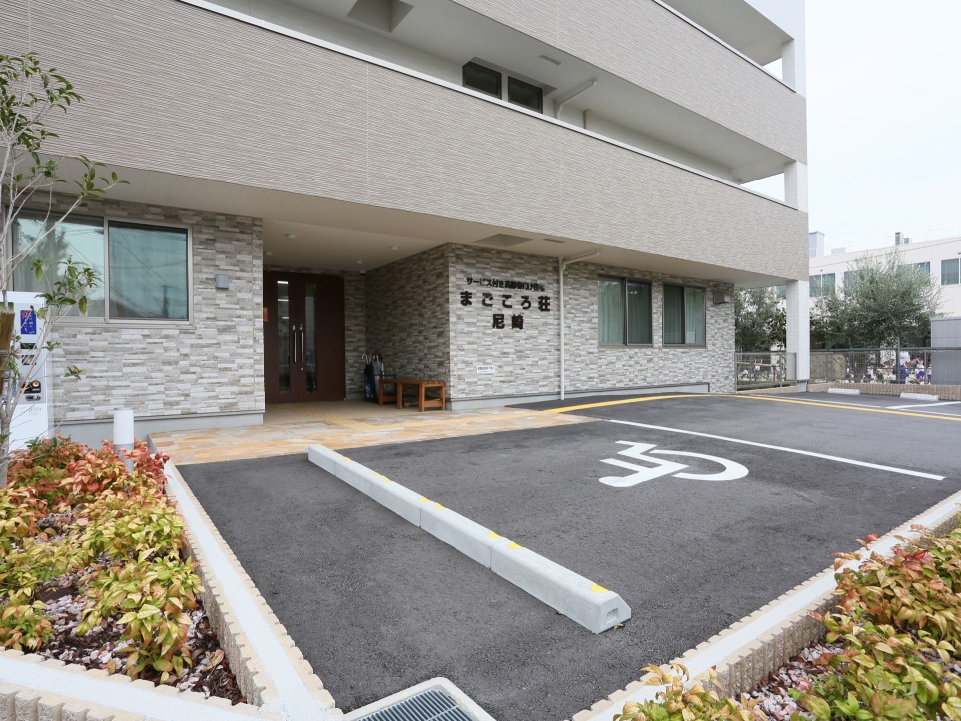 施設の外観はグレーを基調としており、シックな雰囲気である。エントランスに一番近い駐車スペースは、障がい者用である。