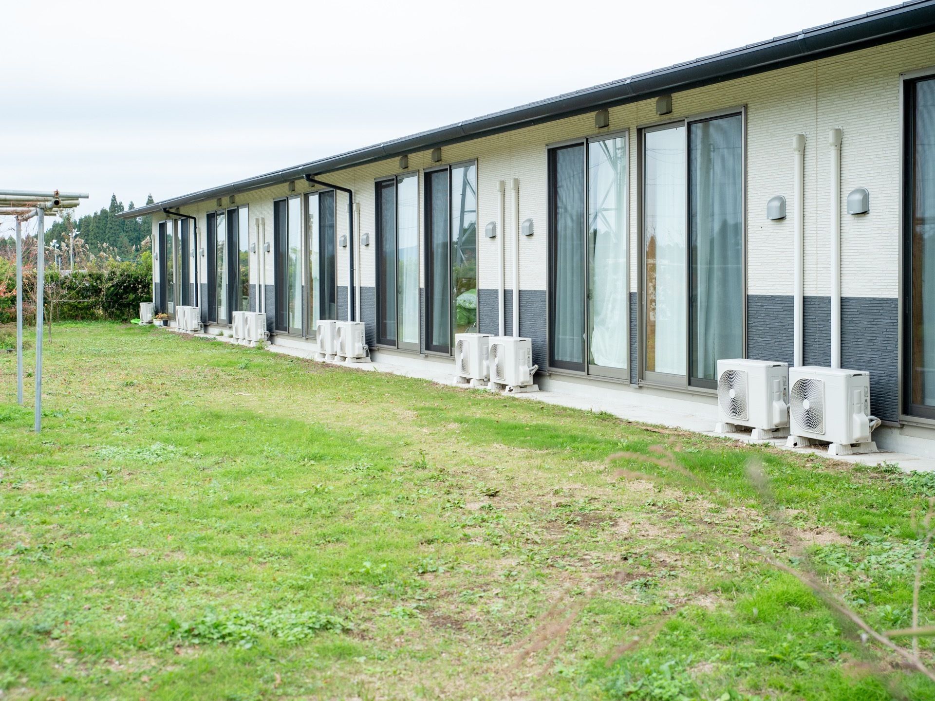 居室からは庭に出ることができる。室外機が並んでおり、芝生部分には洗濯物を干すことができるポールが置かれている。