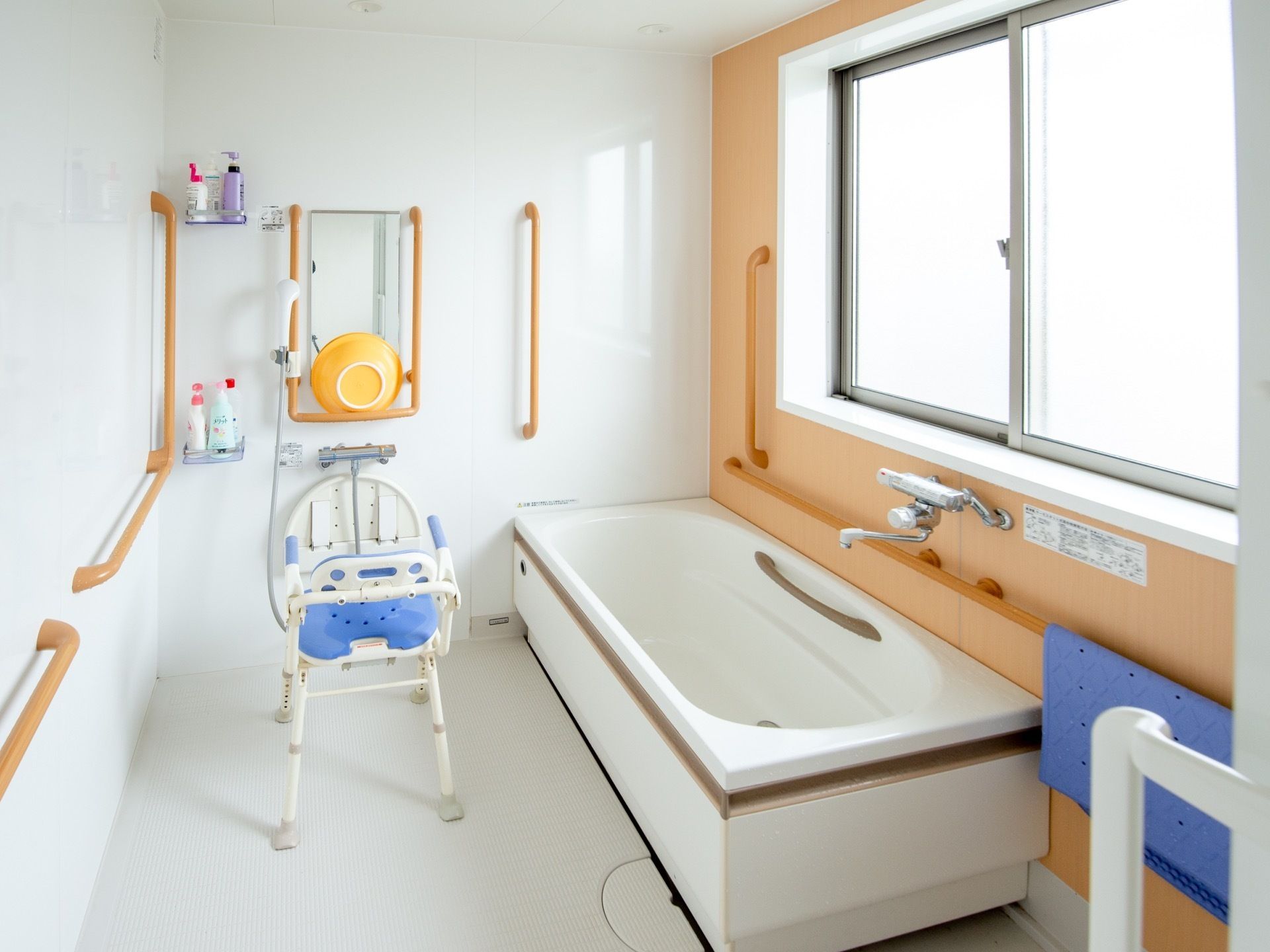 いたるところに手すりが備えつけられた浴室にはシャワーベンチが置かれており、ベンチの高さに合わせた高さに鏡が取りつけられている。