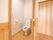 木材をふんだんに使用した、明るみのある居室である。トイレ空間も広々としている。壁側にはＬ型の手すり、ナースコールがある。
