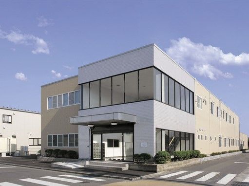 交差点の角に建っている、白とベージュの２色の外壁の建物
