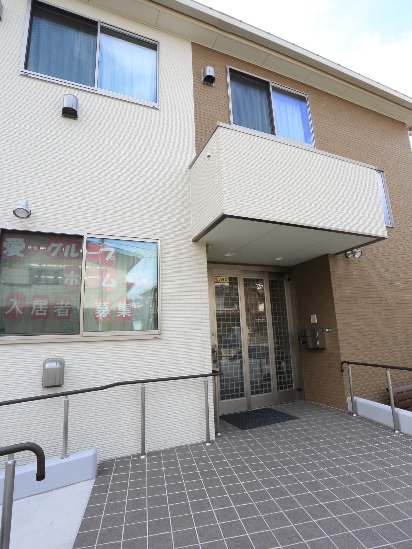 扉の前がタイル張りで広くなっている、屋根が張り出したエントランス