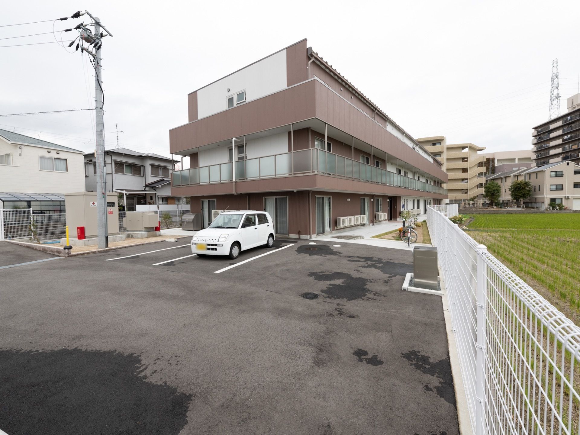 ３階建ての施設は、茶色と白を基本とした外壁で、とてもスタイリッシュなデザインである。２階から上にはベランダがついている。