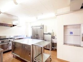 業務用の設備が整っている、壁や天井が白く、広いキッチン