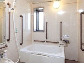 白を基調とした浴室の各所には手すりが設置され、入居者様の安全や日々の使いやすさを考慮した造りとなっている。