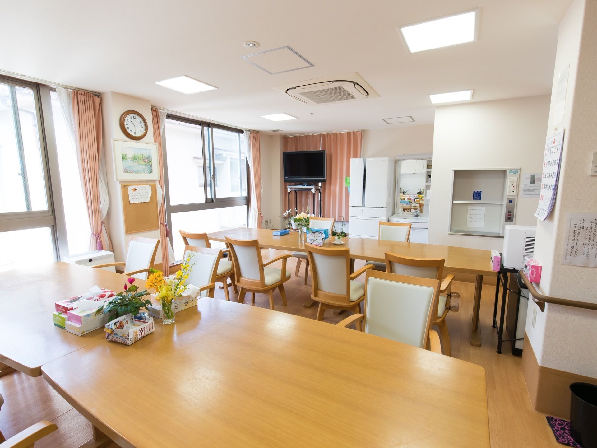 どのテーブルも清潔に保たれている。部屋の隅には高い場所にテレビが設置されている。冷蔵庫があり、横には洗面台もある。