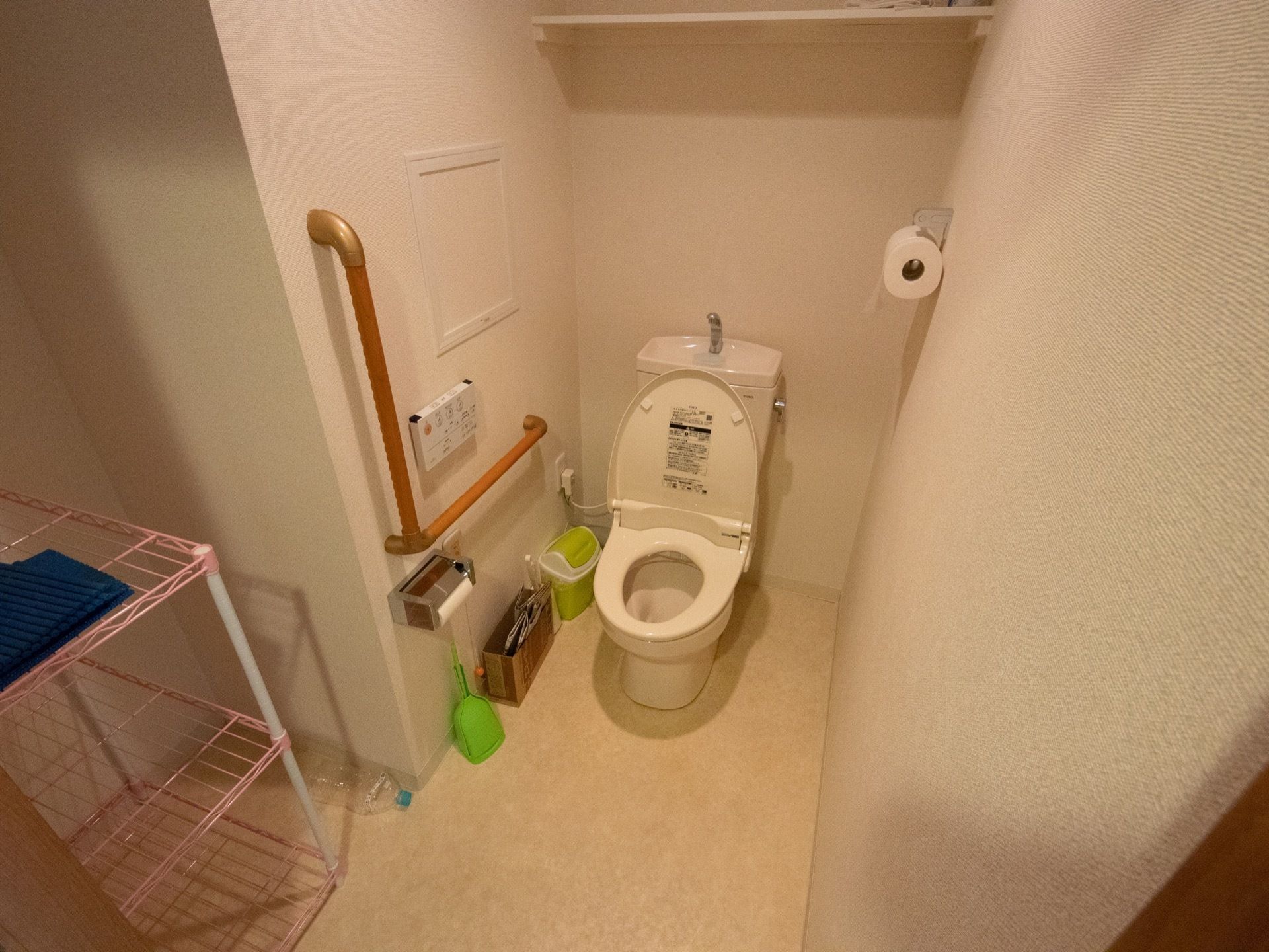 トイレ手前のスペースにスチールラックが設置されており、便器の近くには掃除用具やコンパクトなごみ箱が置かれている。