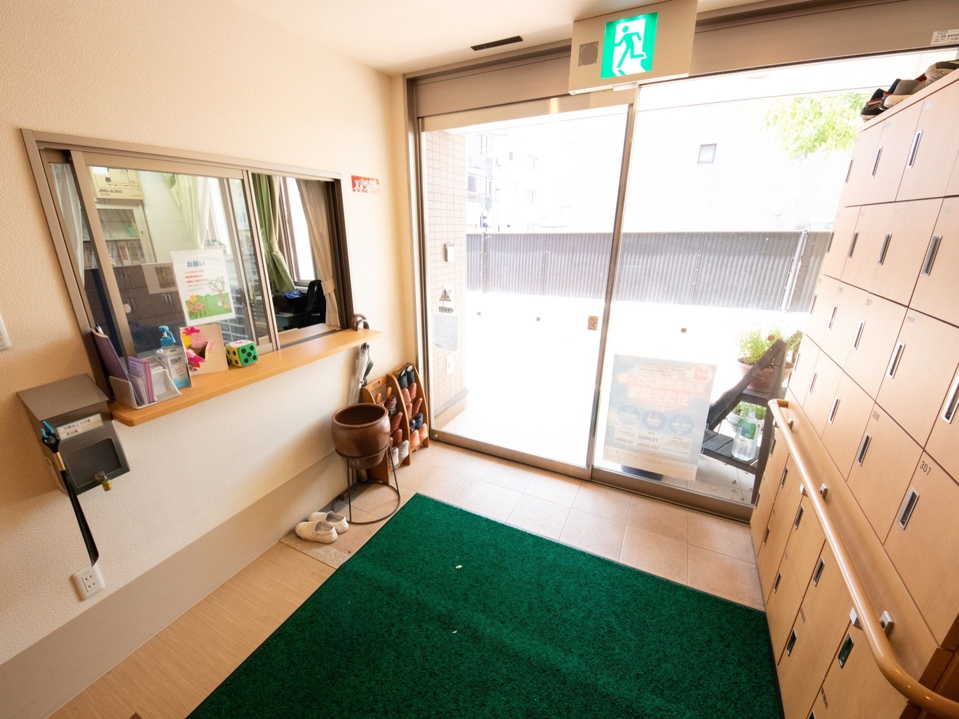 入口すぐ横に受付が設置されており、カウンターに消毒液が置かれている。向かい側には大きな靴箱があり、手すりが取り付けてある。