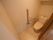白を基調としたトイレで、上方には収納棚が設置されている。居室とは段差のないフラットな床になっている。