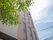 施設の壁は白色とピンク色である。ピンクの壁にたくさんの窓が設置されている。建物のそばに植物があり、緑の葉が茂っている。