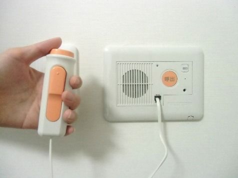 壁に取り付けられた緊急呼び出し用の機器と、それを操作する手