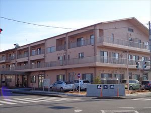 交差点の角に建っており、道路との境界には木が植えられている3階建ての建物