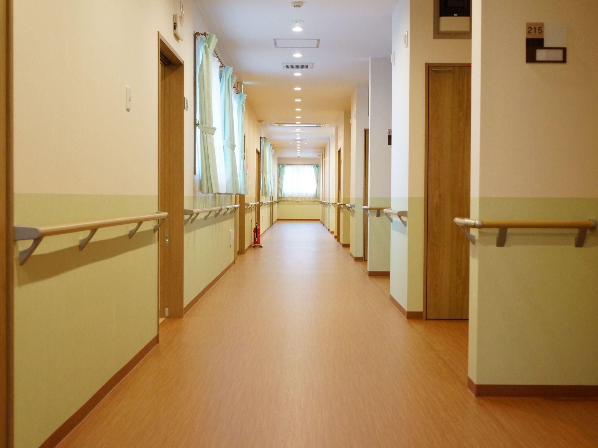共用廊下の腰壁は淡い黄緑色で明るい雰囲気になっている。要所には木製の手すりが設置されており安全性が考慮されている。