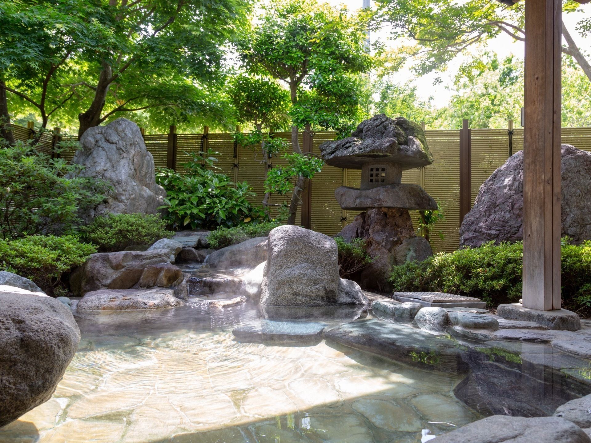 木々が植えられ、大きな庭石がいくつも置かれている庭園と露天風呂