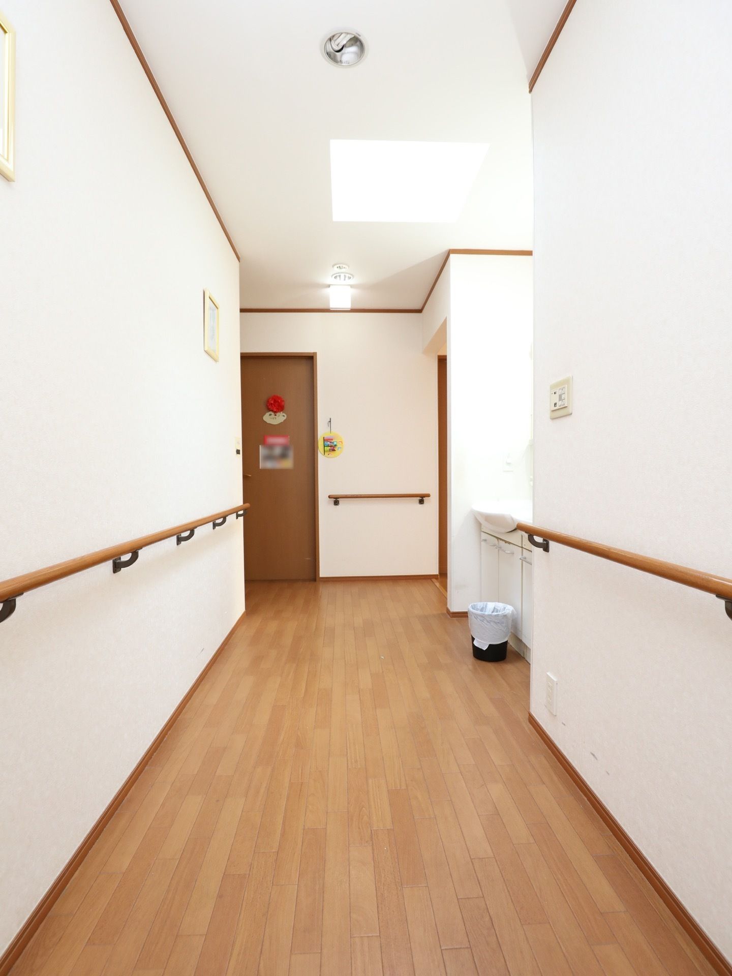 廊下は明るく、清潔感がある白い壁紙。天井は高く、床はフローリングで、壁面には木製の手すりが設置されている。