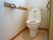 壁側に手すりが設置されている。反対側の壁にはトイレットペーパーフォルダーがある。便器は温水洗浄機能つき。