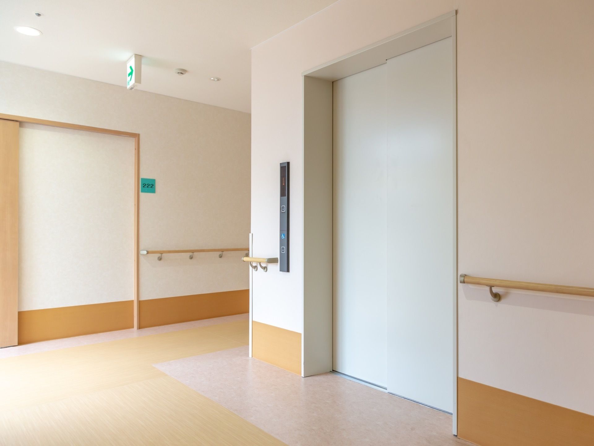 シンプルなデザインのエレベーターには外界からの光が当たっており、淡く照らされている。エレベーターの直前の壁まで、手すりが備わっている。
