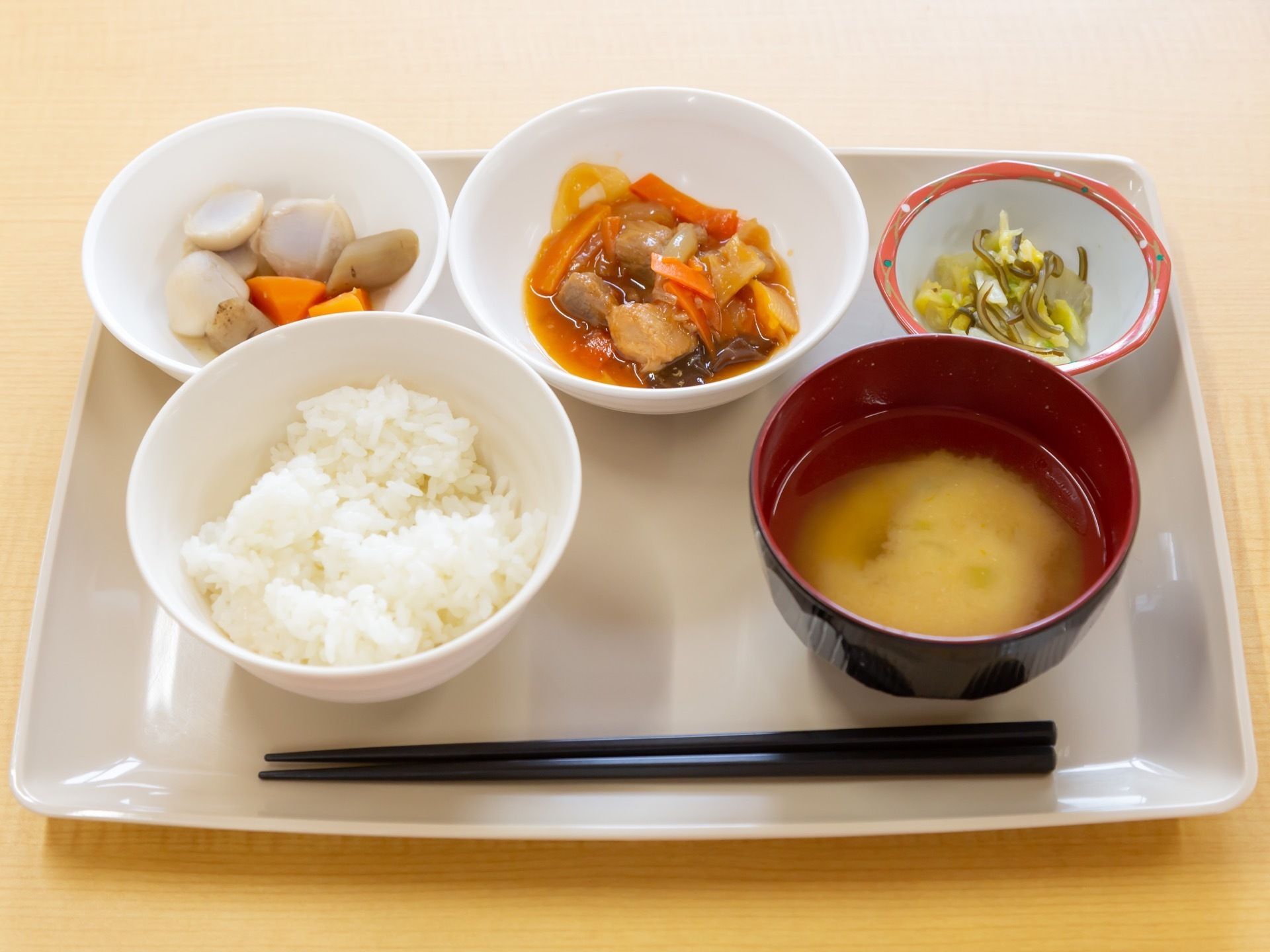 施設で提供される食事の一例として、お盆上にお皿を丁寧に配置した和膳が表示されている。メニューには野菜がふんだんに使用されている。