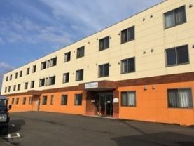 三階建ての建物は、一階部分の外壁がオレンジで塗装してあり目を引く。外壁と色を分けているので玄関が分かりやすい。