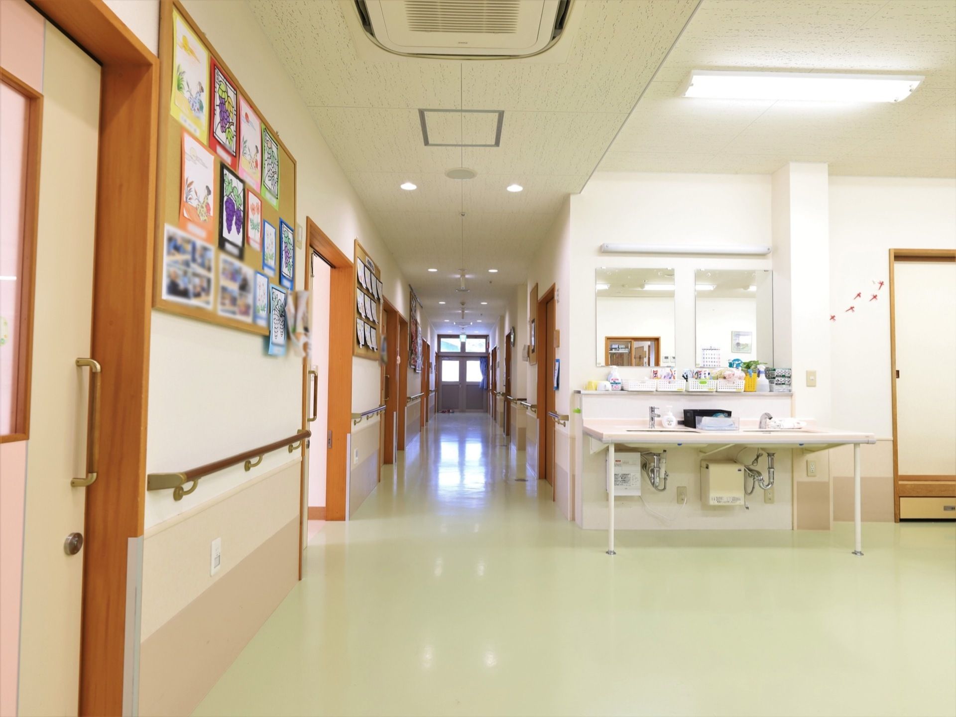 廊下は広々としていて、一角には洗面スペースが設置されている。壁には、入居者様が描いた絵が飾られている。