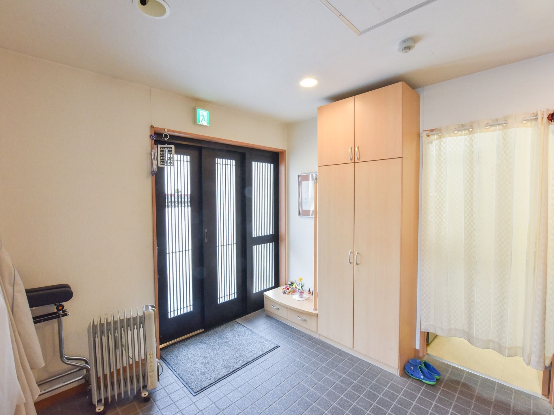 入口は扉３枚分の引き戸となっている。玄関横に大きな靴箱が置かれている。簡単な外出用にサンダルが用意されている。