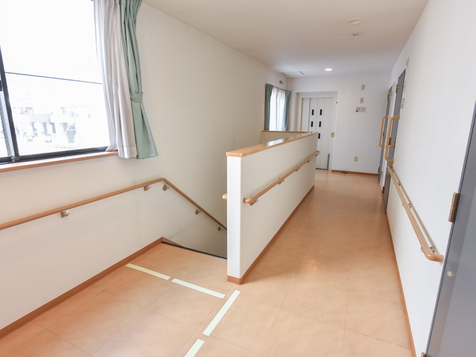 廊下の各所に窓が設けられていて明るい空間である。廊下の壁の他に、居室の扉の横にも縦向きに手すりが設置されている。