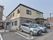 建物はグレーとベージュのツートンの２階建てである。建物前は駐車スペースがある。入口横に自動販売機が置かれている。