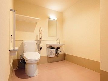 白を基調とした明るいトイレで、車椅子のままでもゆったりと入られるほどの広さがある。中には鏡と洗面台が設置されている。