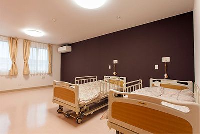 ゆったりとした広めの二人部屋の居室である。キャスター付きで移動もでき転落防止のベッドフェンスが付けられた介護ベッドが２台置かれている。