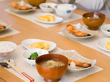 焼き鮭、卵焼き、貝の味噌汁、ほうれん草の胡麻和え、ごはんの５品の食事が用意されている。蝶々型の箸置きやお椀、お皿にもこだわりが見られる。