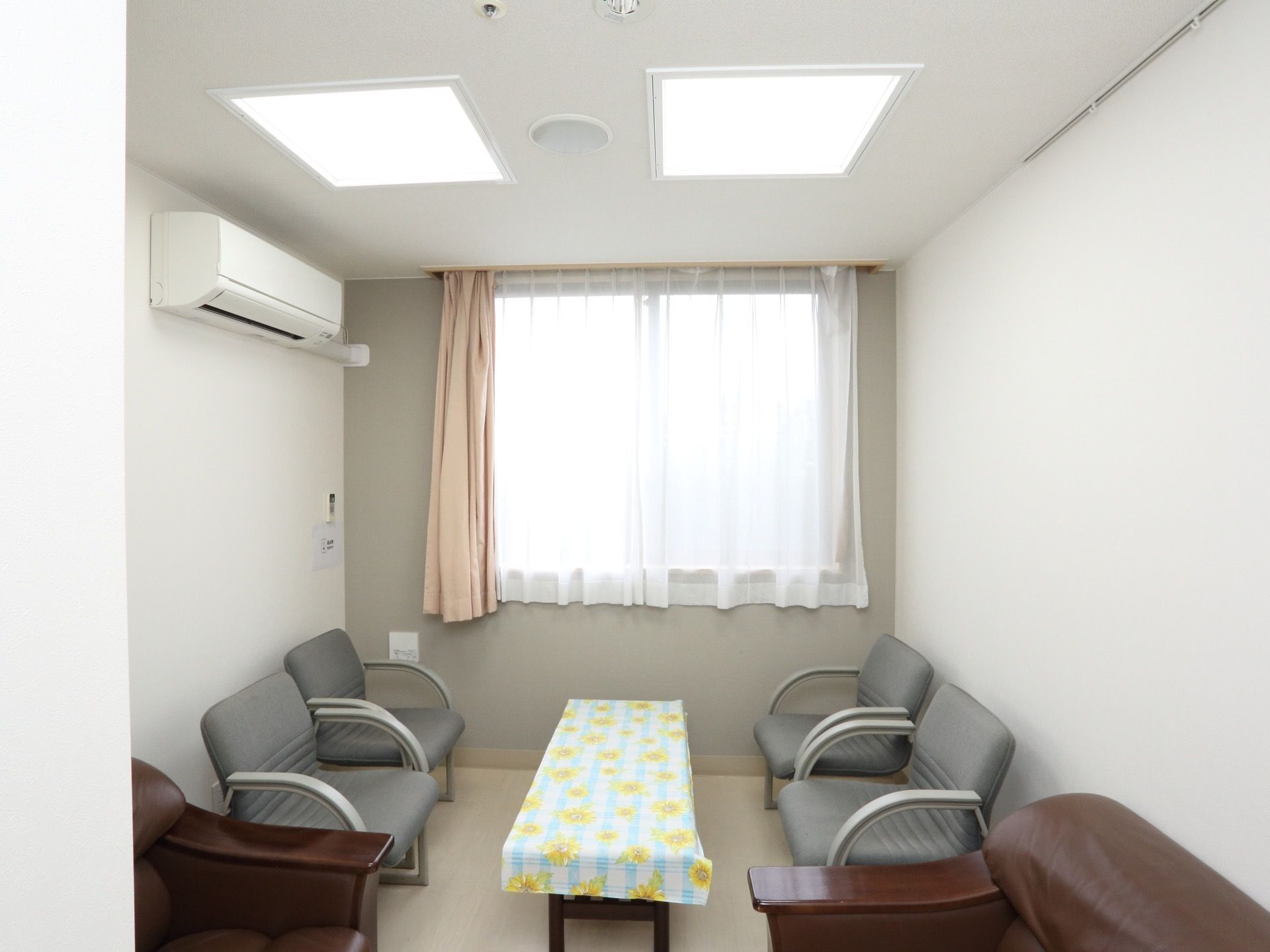 談話室の真ん中にローテーブルがあり、黄色い花柄のカバーが掛けてある。その左右に、４脚の椅子が置いてある。